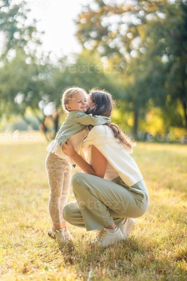 Young mother and little daughter hugging and playing together in autumn park in Prague, Europe. High quality photo