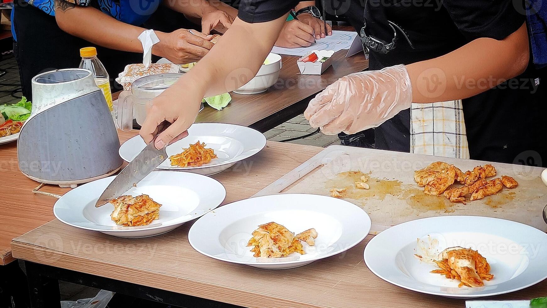 Slicing grilled chicken to serve on a plate with a side dish of vegetables photo