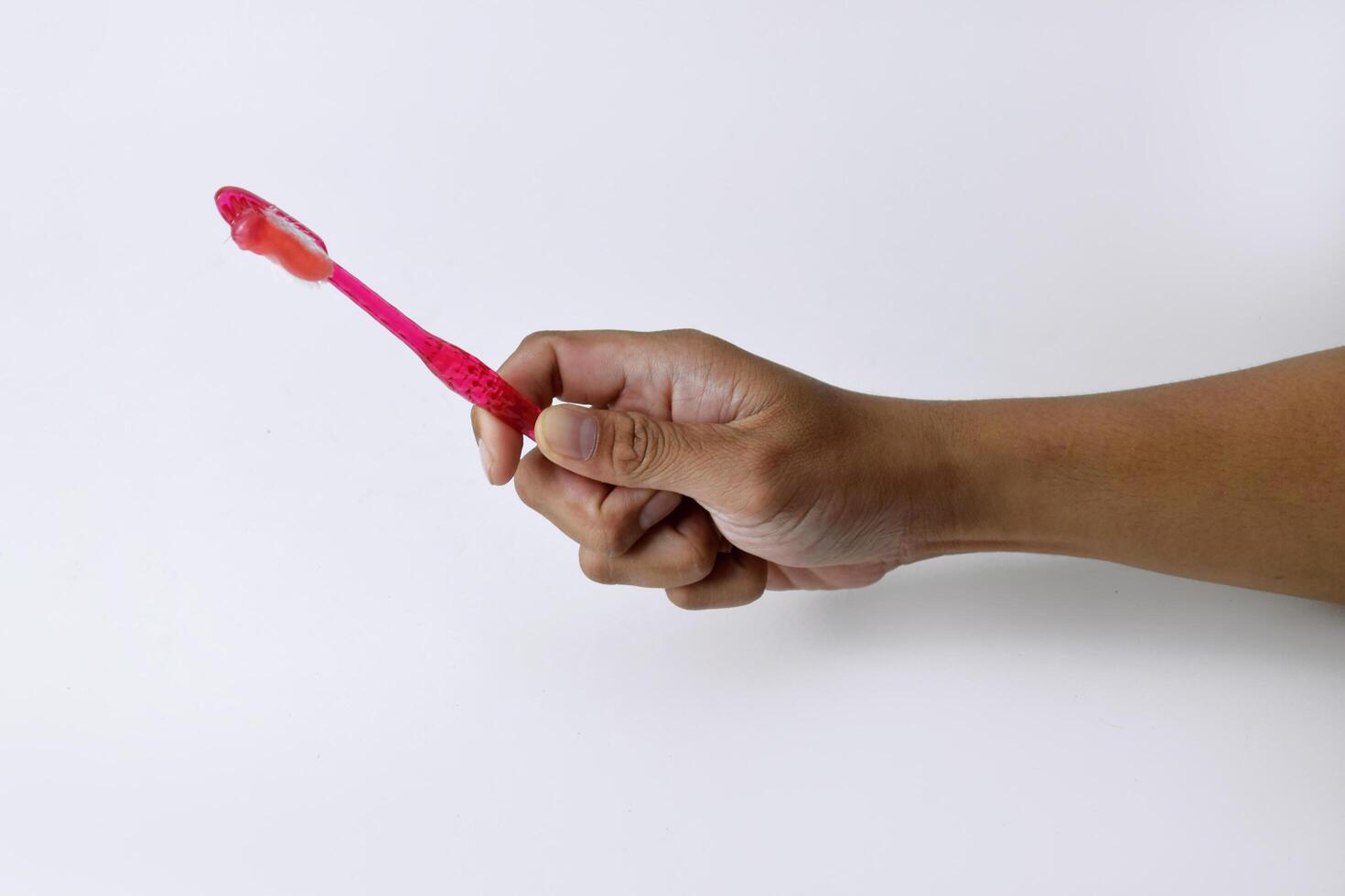 Male hand holding a red and white toothbrush containing toothpaste photo