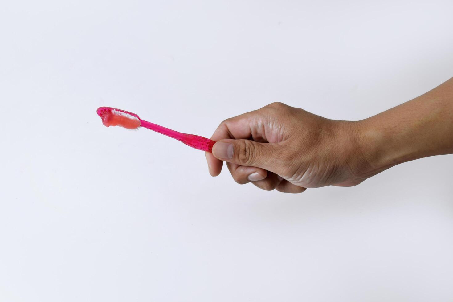 Male hand holding a red and white toothbrush containing toothpaste photo