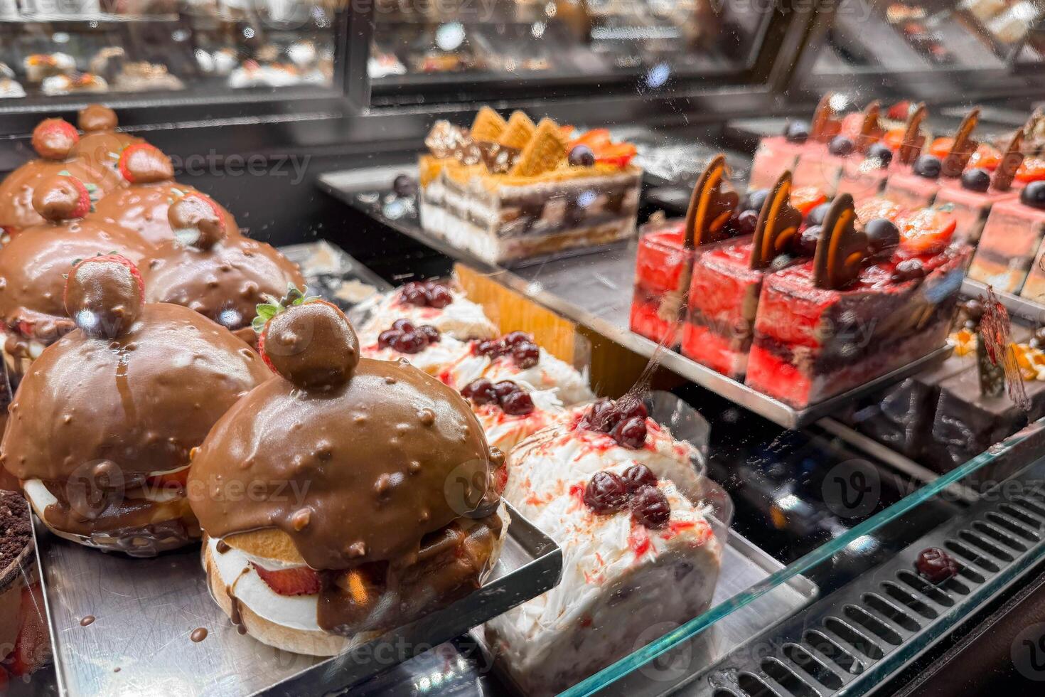 Close-up photo of a glass counter in a bakery or pastry shop with sweets, sponge cakes and chocolate cakes.