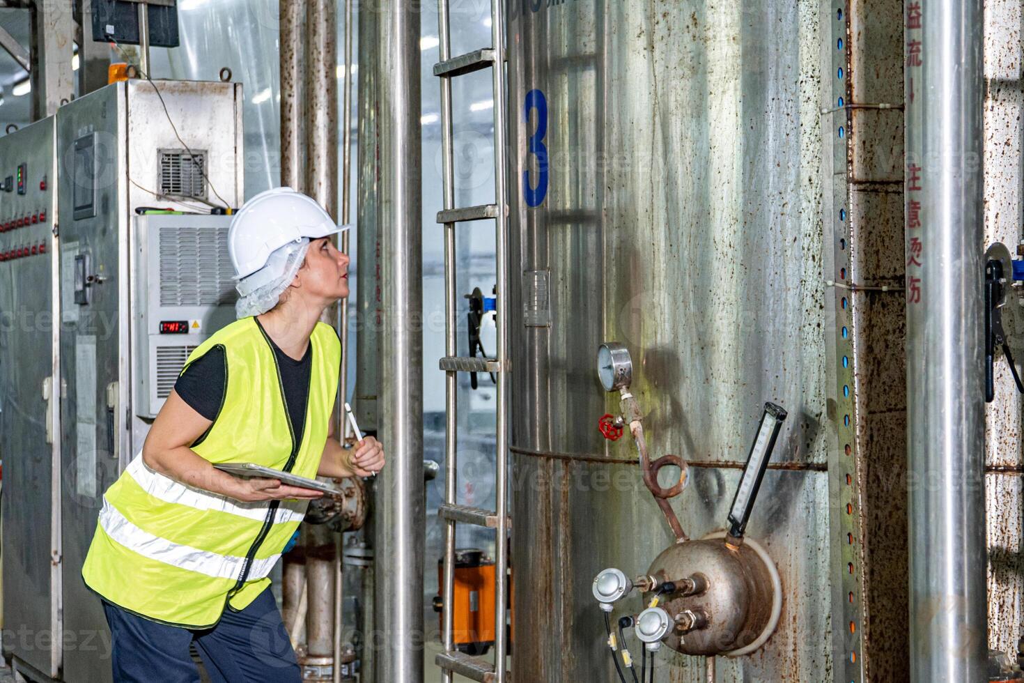 Female industrial engineer wearing a white helmet while standing in a heavy industrial factory photo