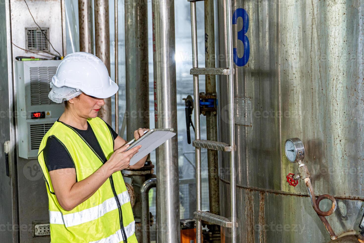 Female industrial engineer wearing a white helmet while standing in a heavy industrial factory photo