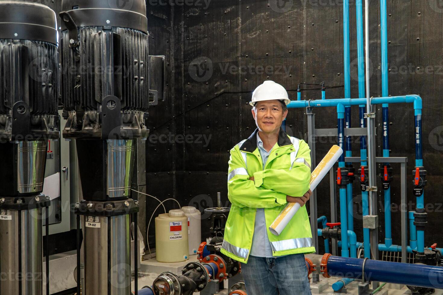 asian man worker in protective uniform and with hardhat using tablet for checking temperature in pipes Factory interior. photo