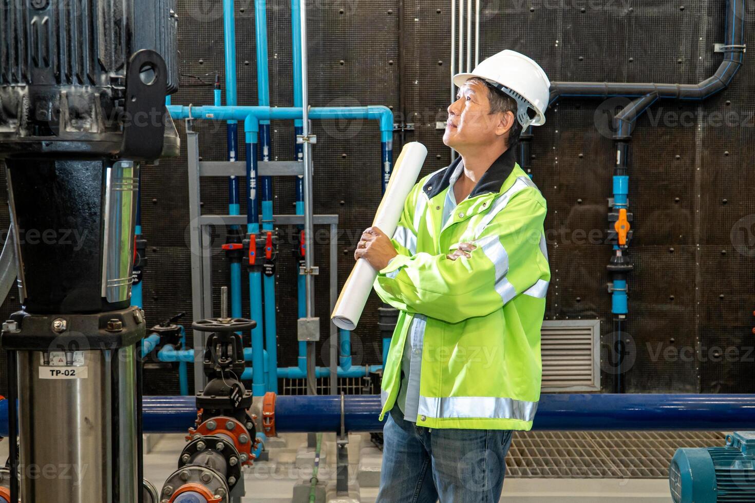 asian man worker in protective uniform and with hardhat using tablet for checking temperature in pipes Factory interior. photo