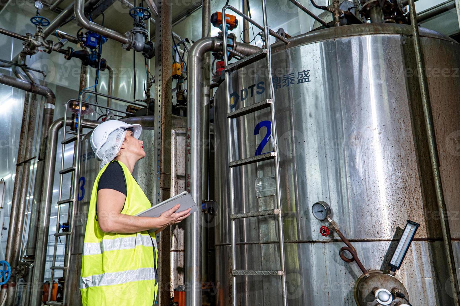 Female industrial engineer wearing a white helmet while standing in a heavy industrial factory photo