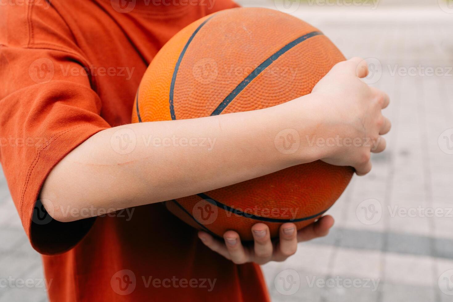 teenage boy wrapped his hands around the ball after playing basketball photo