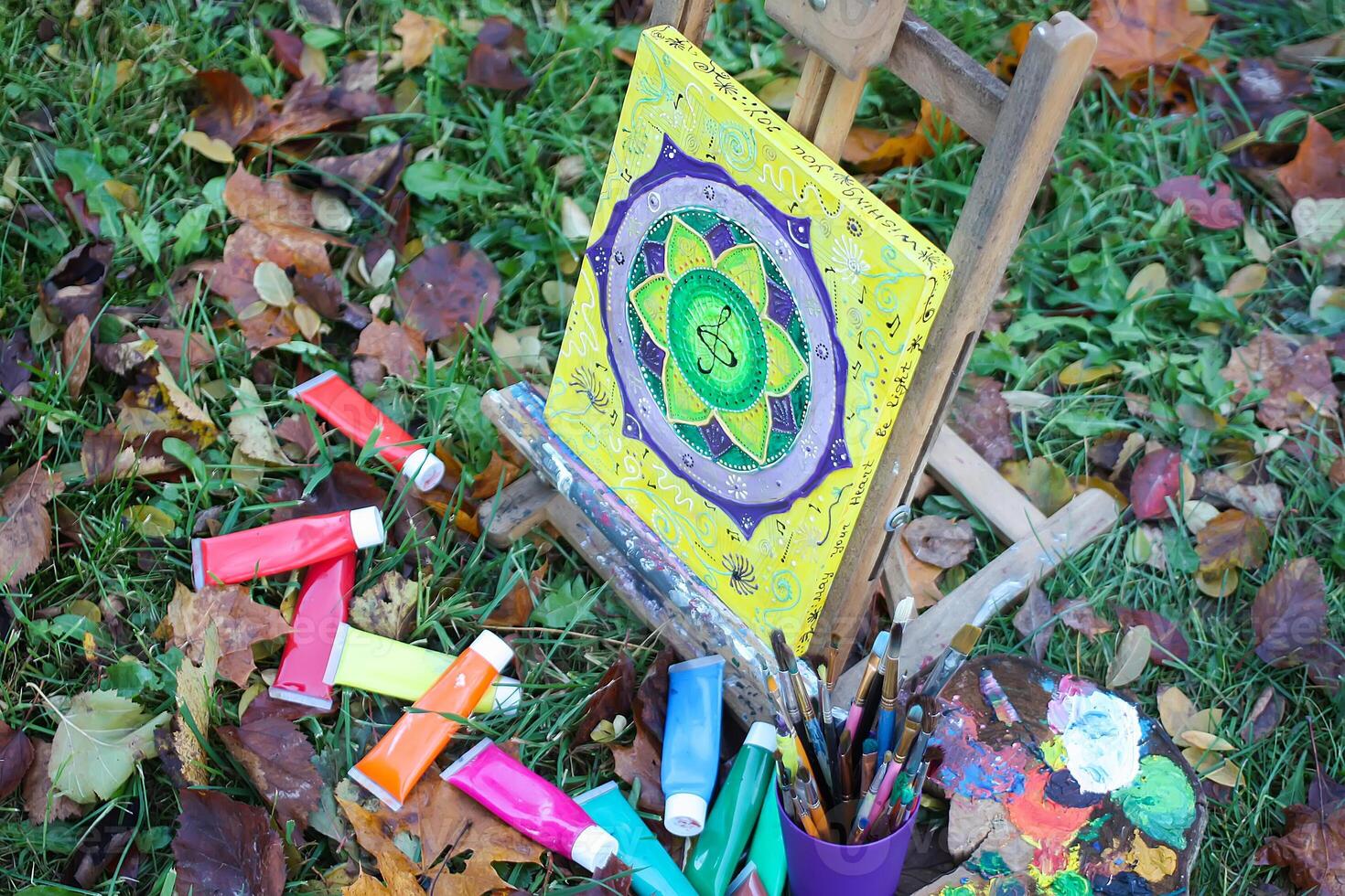 Easel with paints and painting on canvas in autumn park photo