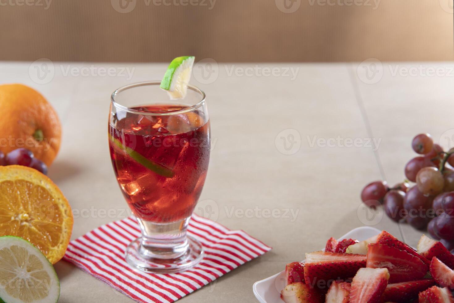 Close-up of glass cup with homemade summer wine in foreground next to plate of chopped strawberries on ceramic table photo