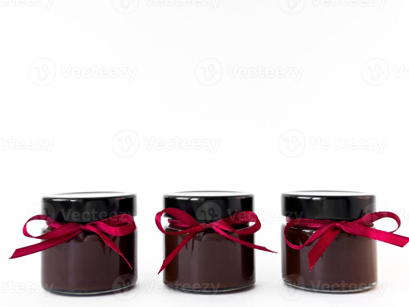 Elegant trio of chocolate jars with red ribbons on white background photo