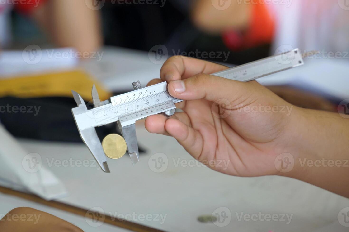 Hand holding Vernier calipers to measure the diameter of coins. Concept of science laboratory, precision measuring instruments, measurement photo