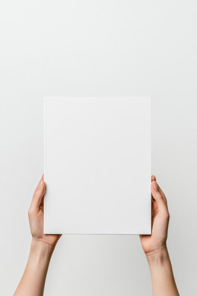 person is holding blank white book against light background, showcasing minimalist design. This image conveys simplicity and creativity, perfect for various uses photo