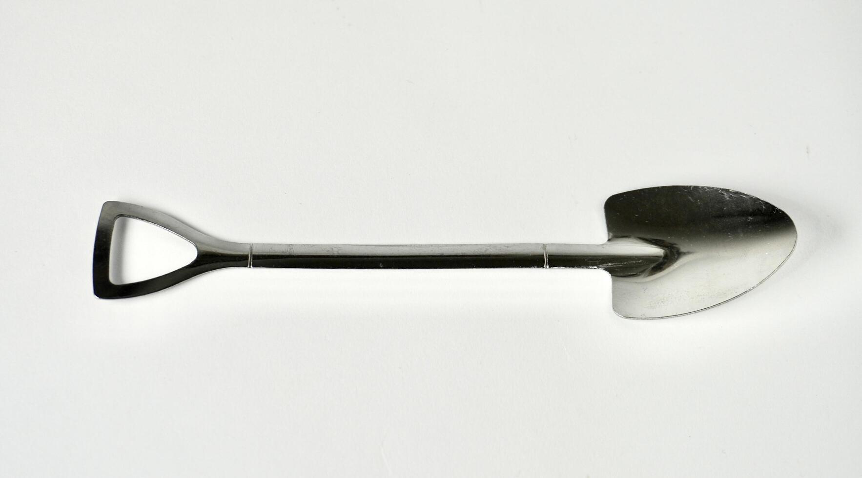 Metal small spoon object with silver gray shovel shape isolated on horizontal white background. photo
