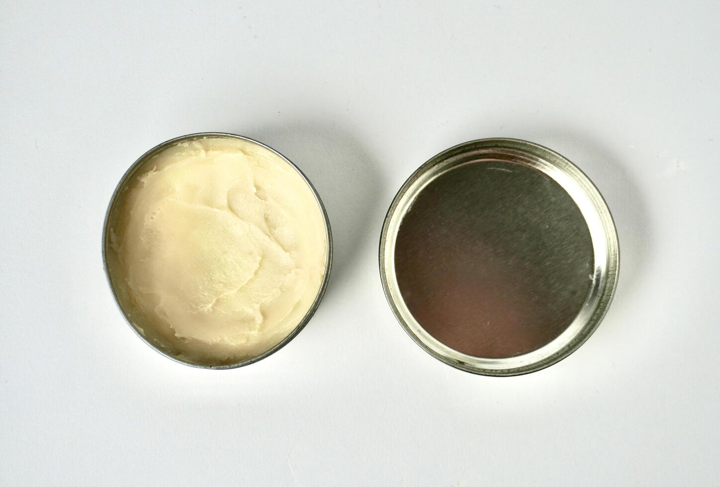 Deodorant cream skin care product inside round metal tin jar container with separated lid isolated on horizontal ratio background. photo