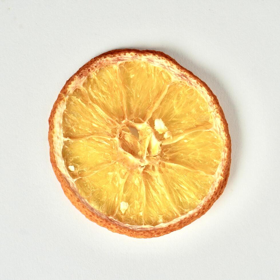 One piece of dried orange fruit slice isolated on square white background from above angle view. photo