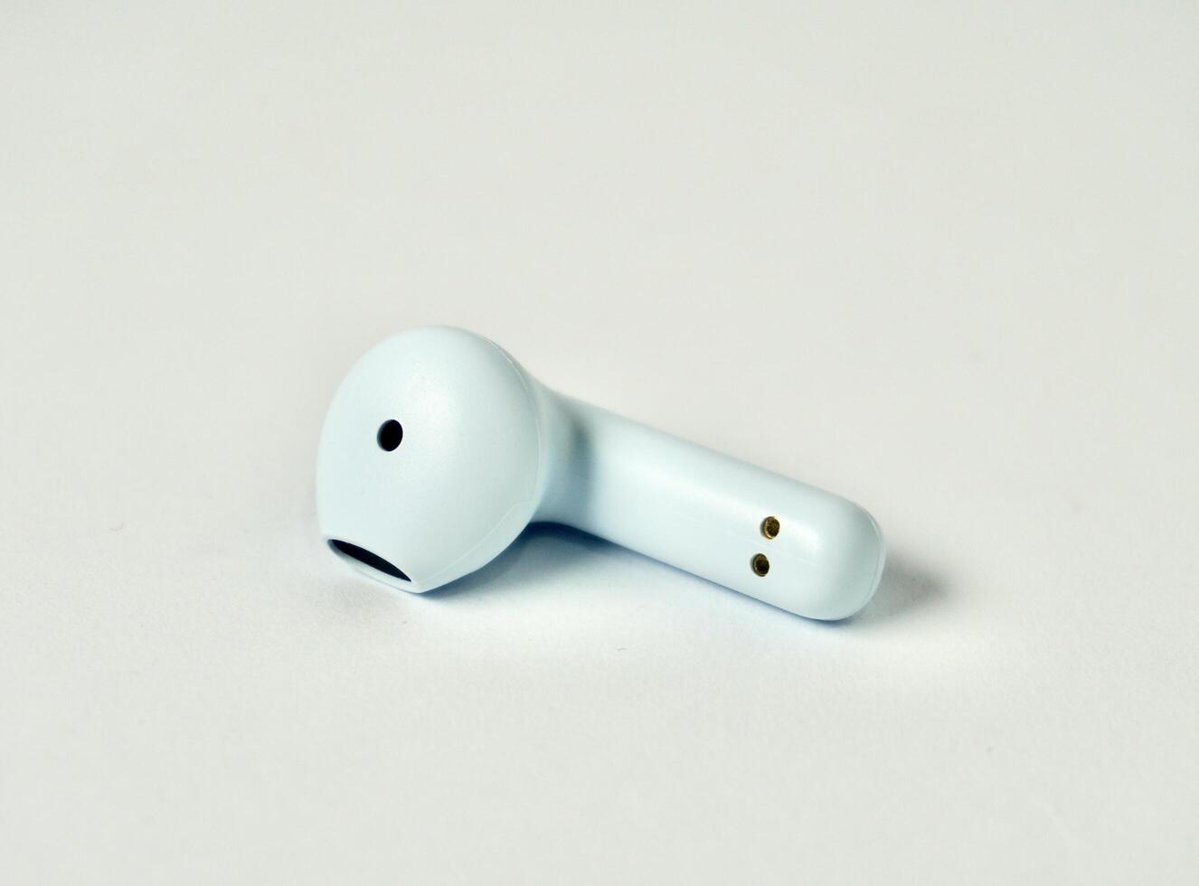 One piece of wireless blue bluetooth earphone isolated on horizontal white background. photo