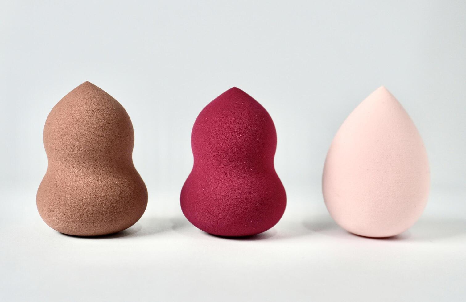 Three curvy and tear drop make up tool soft beauty blender sponge set isolated on horizontal white background. photo