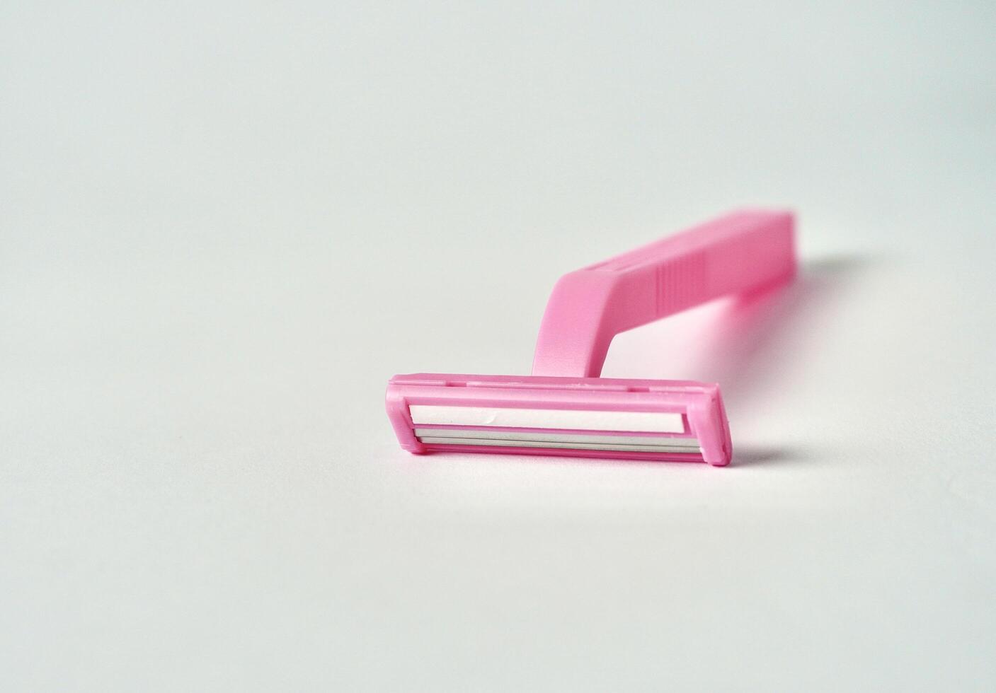 One pink colored razor tool object isolated on horizontal ratio copy spaced white background. photo