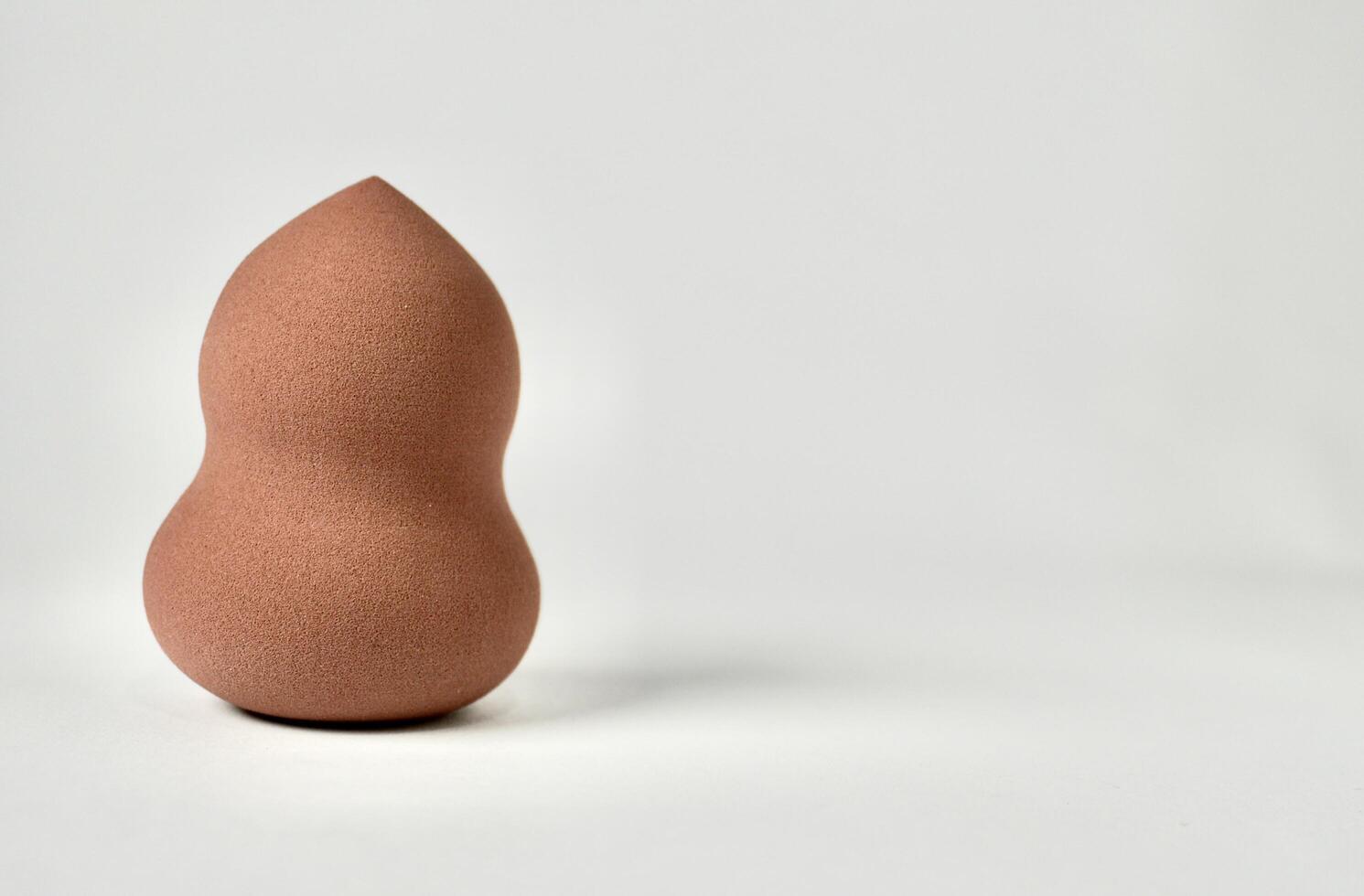 One brown curvy make up tool soft beauty blender sponge isolated on horizontal copy spaced white background. photo