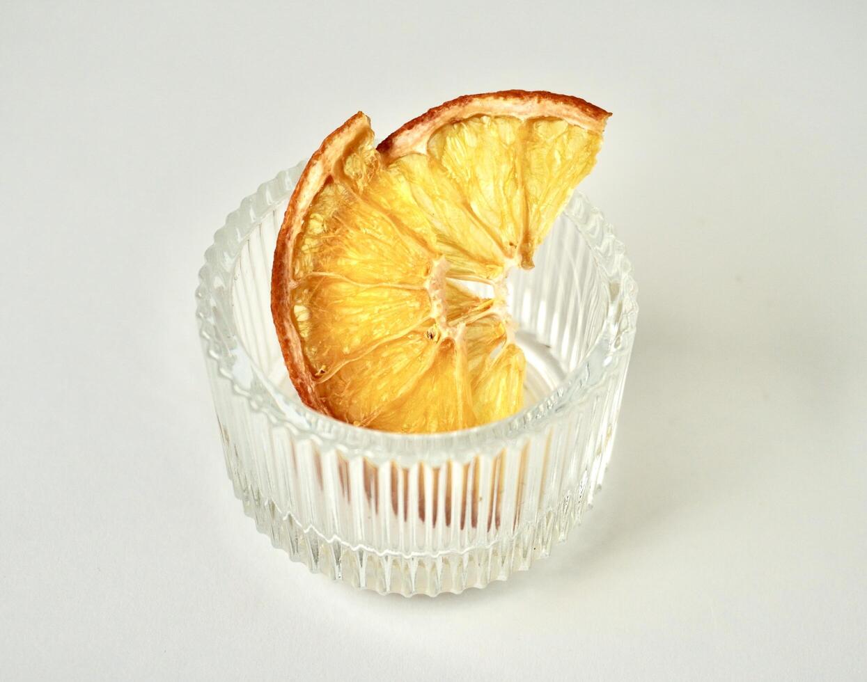 Sliced in half dried orange fruit in small round glass bowl container isolated on horizontal white background. photo