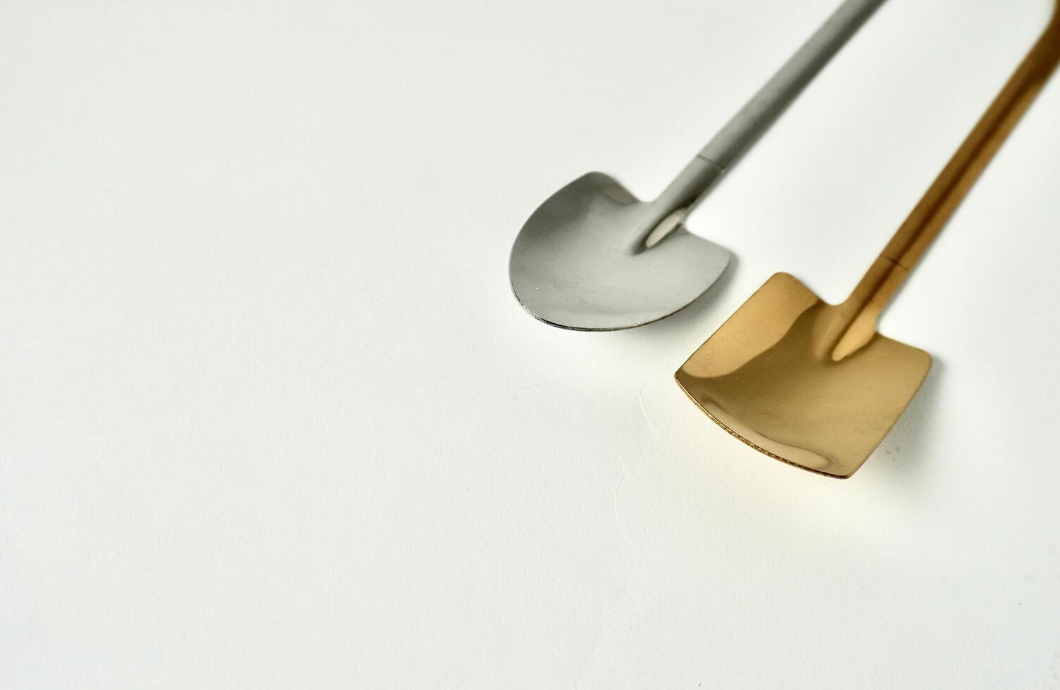Metal small spoon objects with silver and gold shovel shape isolated on horizontal copy spaced white background. photo