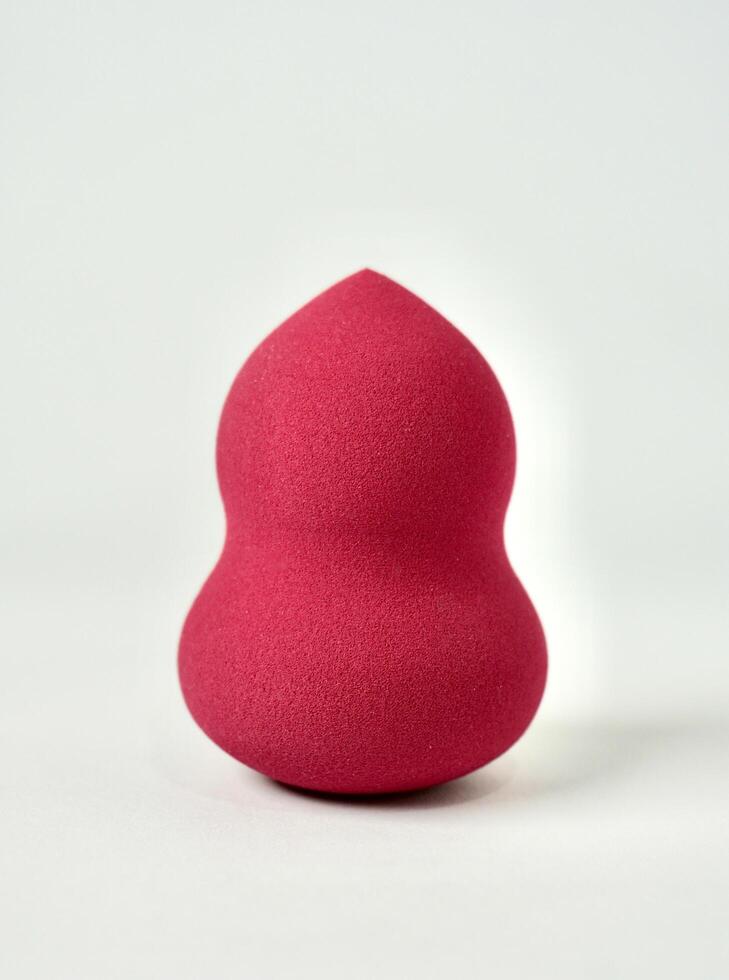 One pink red make up tool soft beauty blender sponge isolated on vertical white background. photo