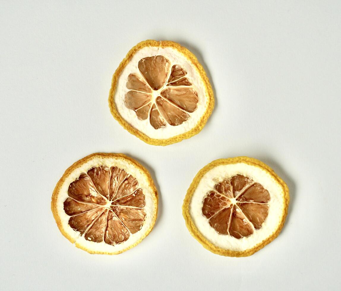 Three dry lemon citrus slices isolated on horizontal white background from above angle view. photo