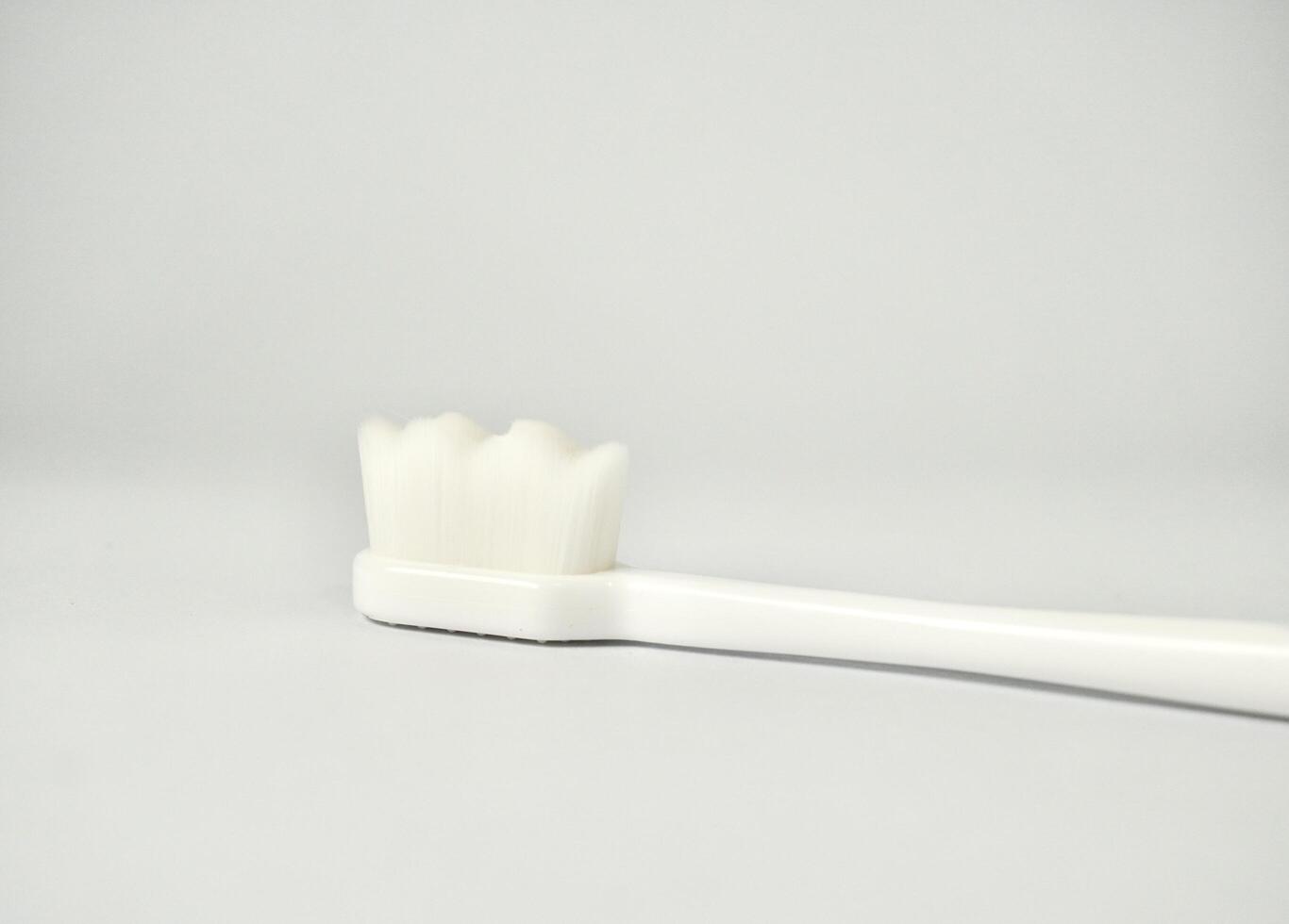 One white plastic toothbrush tool with ultra soft bristles isolated on horizontal copy spaced white background. photo