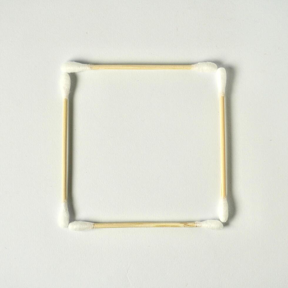 Square cotton buds frame with brown wooden bamboo handle isolated on copy spaced white background. photo