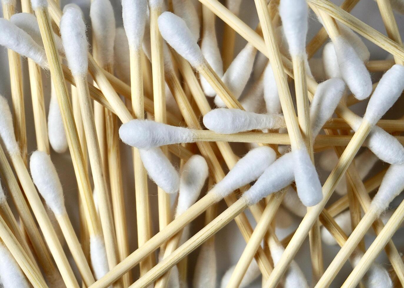 Pile of cotton buds with brown wooden bamboo handle isolated on horizontal full frame white background. photo