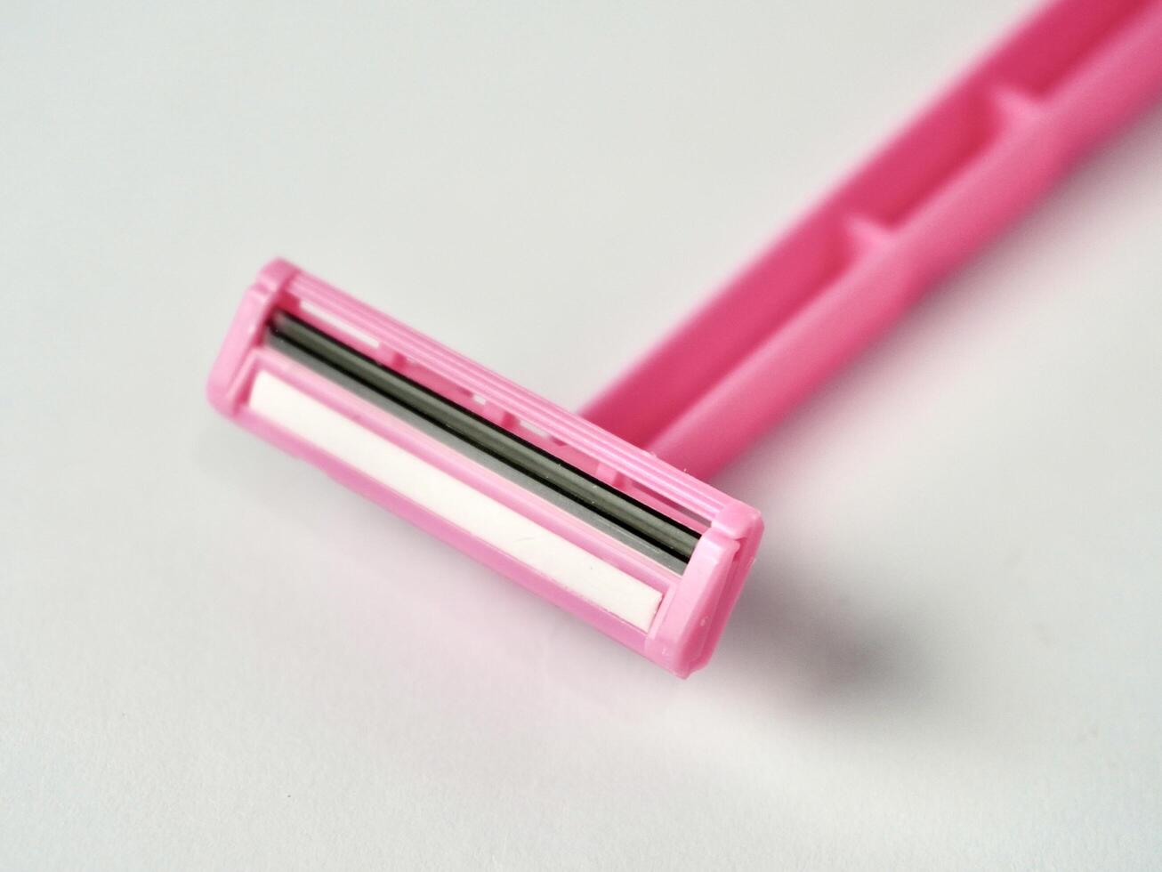 Close up one pink colored razor tool object isolated on horizontal ratio white background. photo