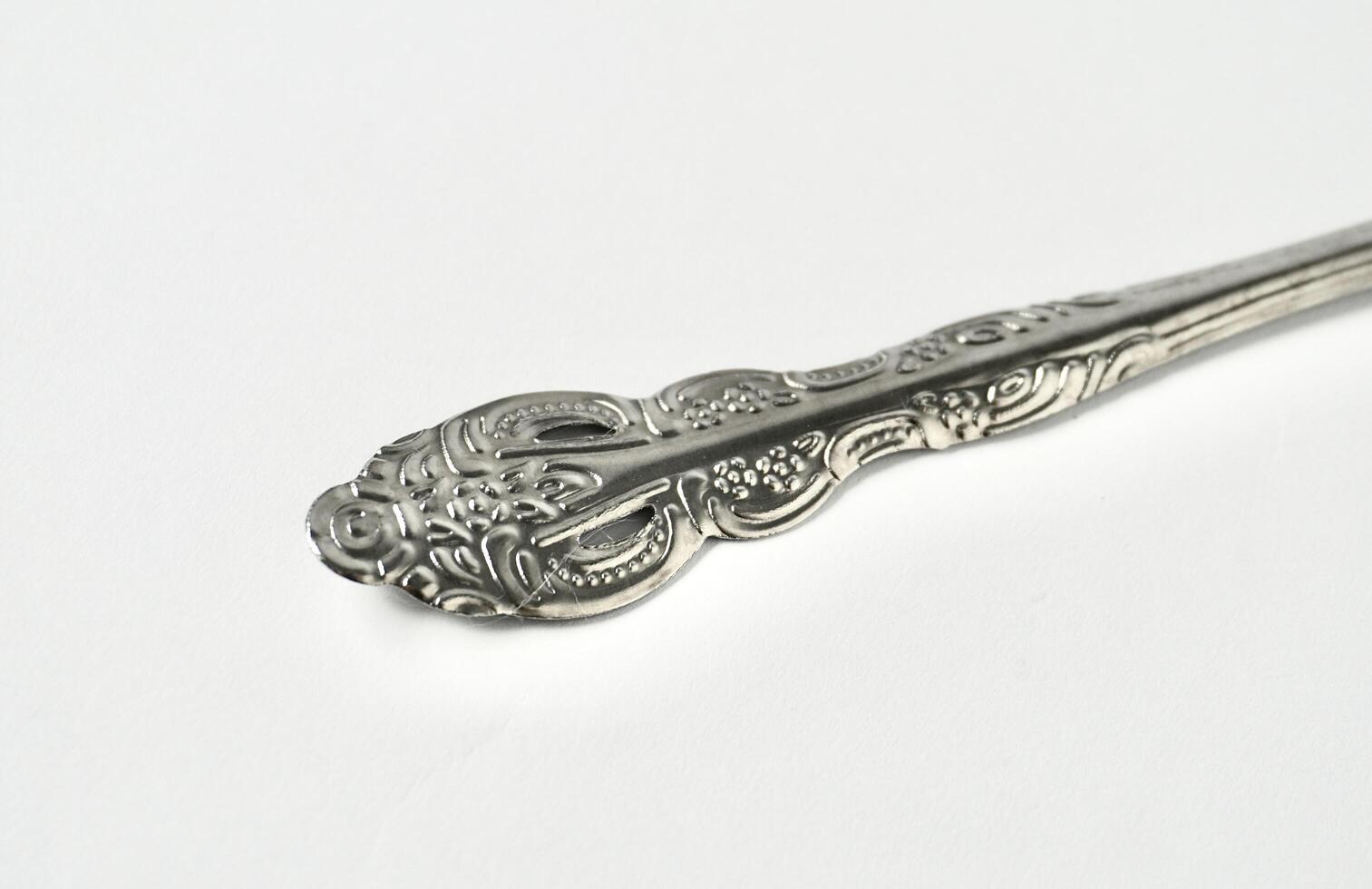 Close up decorative silver spoon tableware object handle isolated on horizontal white background. photo