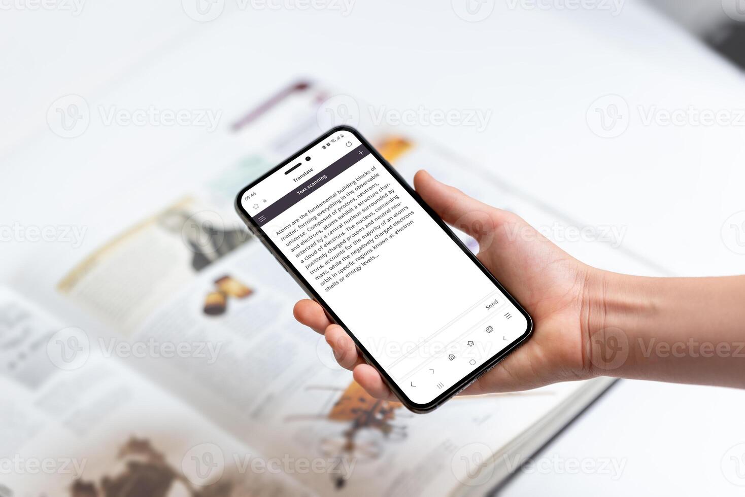 Hand holding smartphone scanning text in book, representing technology use for extracting knowledge, information, and details from printed materials photo