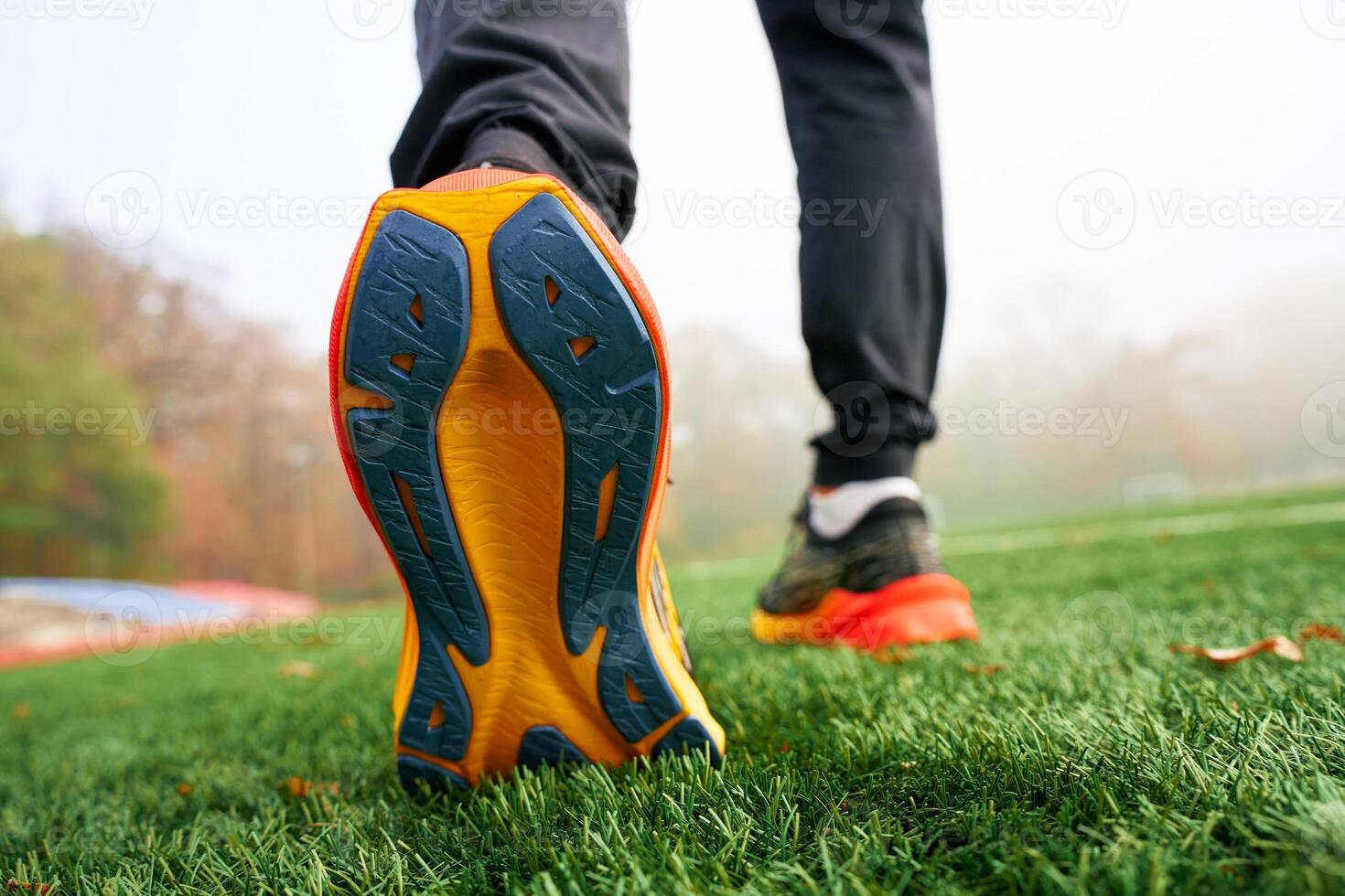 Close-up of running shoes sole with athlete walking on artificial grass. Sportsman legs in sport sneakers on green grass photo
