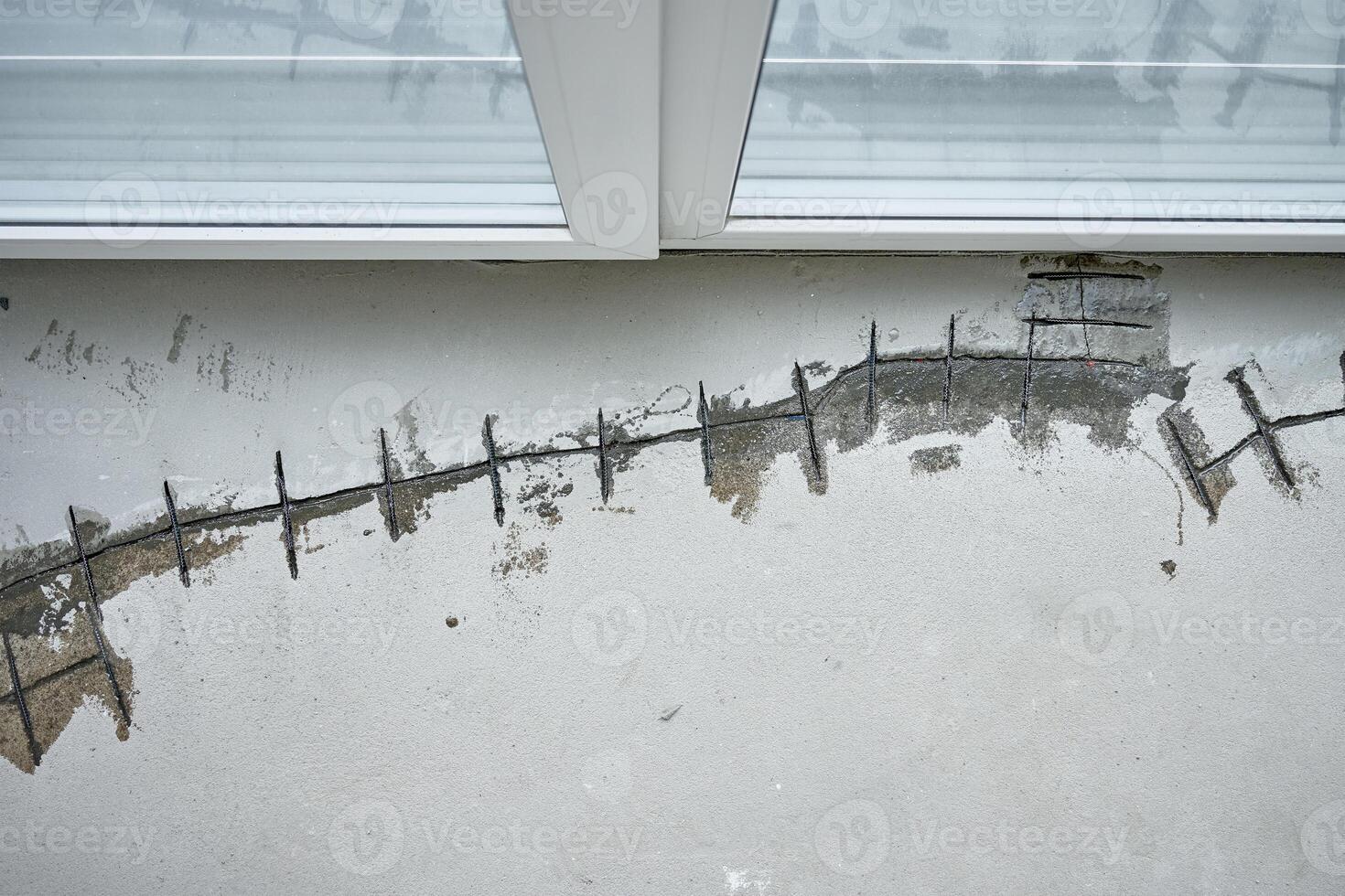 Repairing cracks in concrete floor near window using sealant. Renovation process in house under construction photo