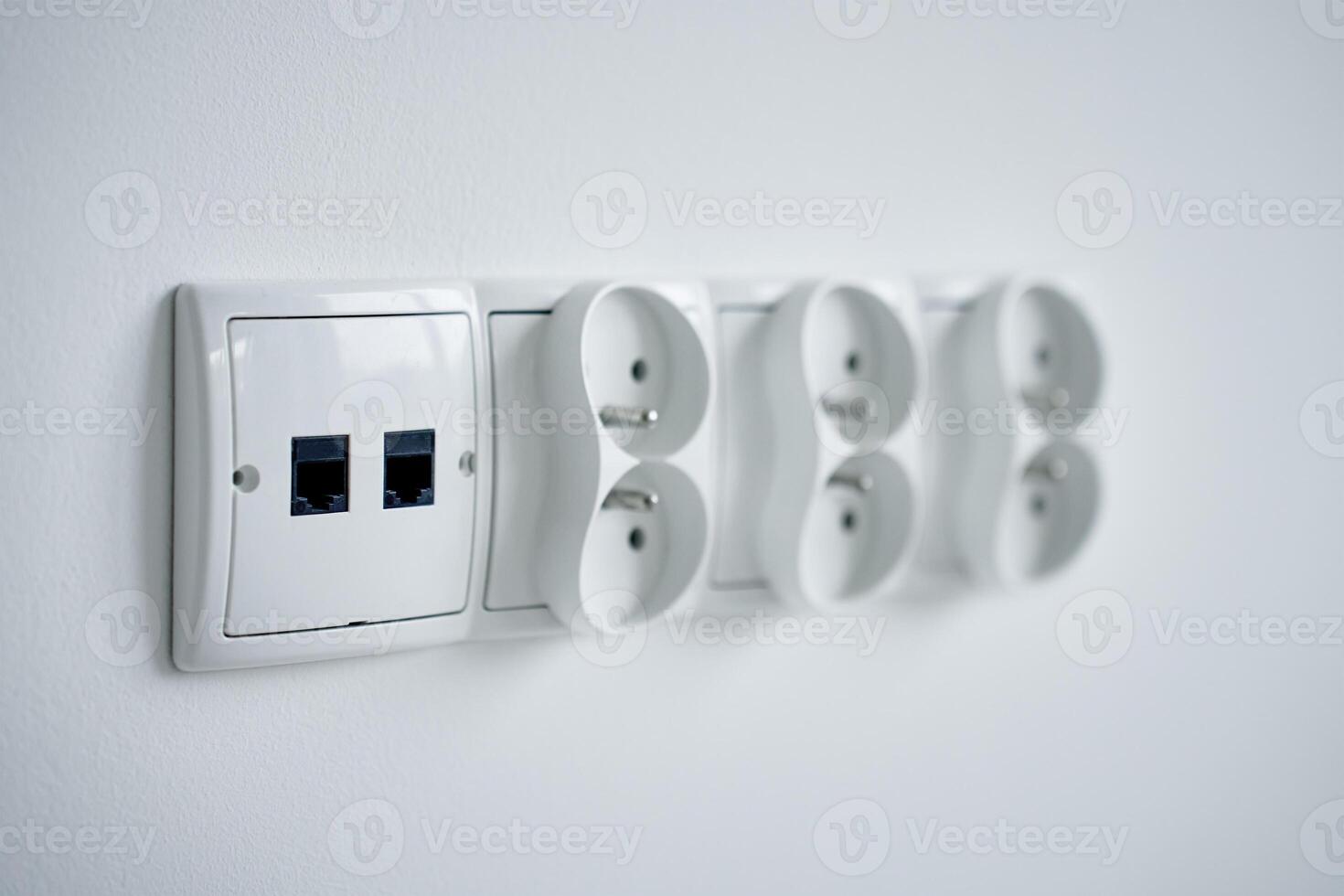 Close-up of white electrical sockets and ethernet ports on white wall photo