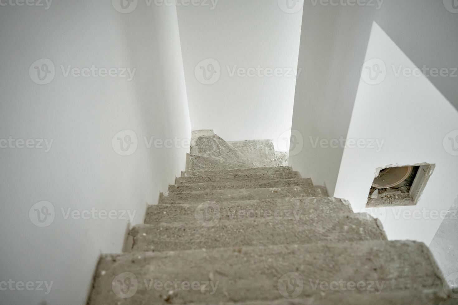 Empty apartment with unfinished concrete staircase and white walls undergoing renovation. Interior of building under construction photo