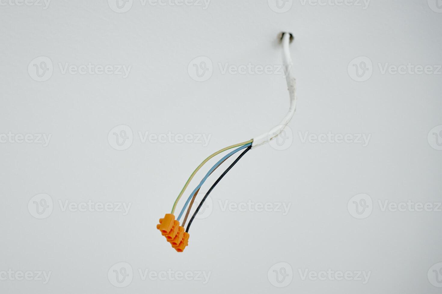 Close-up of electrical wires extending from white wall. Electrical work during apartment renovation. Electricity cable in new apartment photo