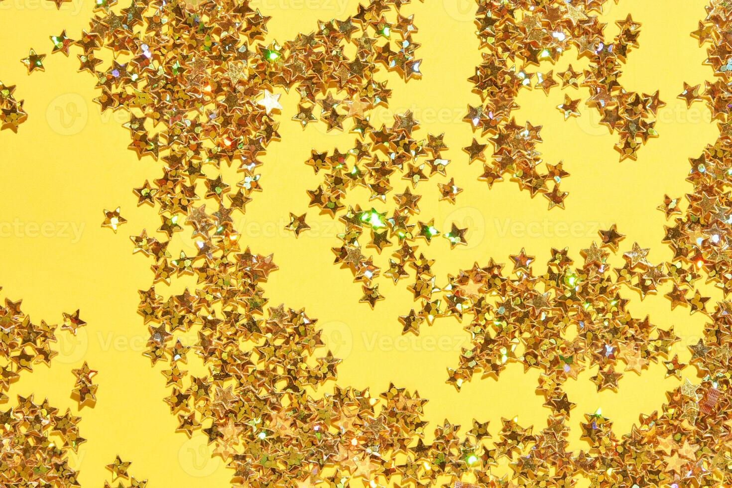 Glittering gold star confetti on bright yellow background. photo