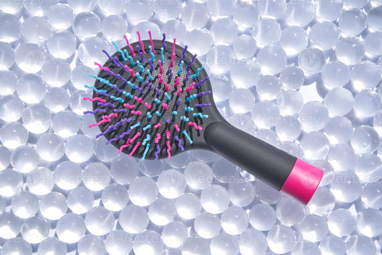 Vibrant hairbrush on translucent gel balls background for beauty and wellness trends. photo