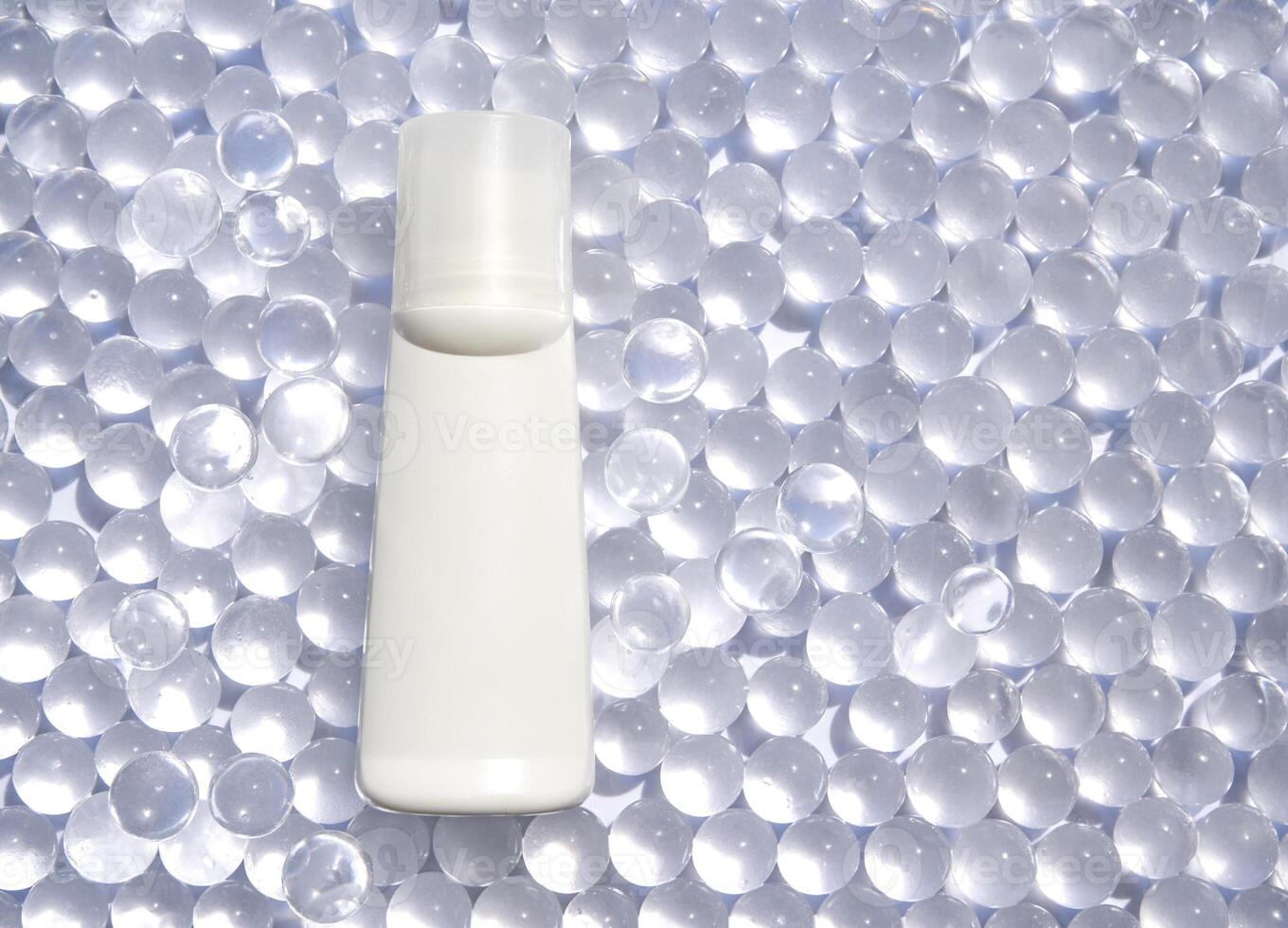 Minimalist white cosmetic bottle on transparent bead background for elegant spa and skincare branding. photo