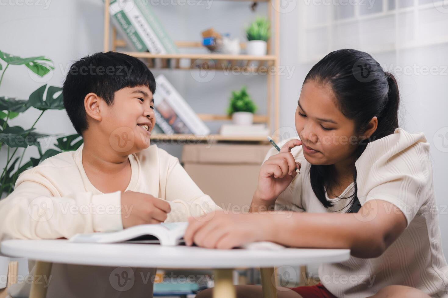 Teacher or sister helping boy writing lesson and learning to write, Female tutor helping little elementary school boy with homework during individual lesson at home, Education home school concept. photo