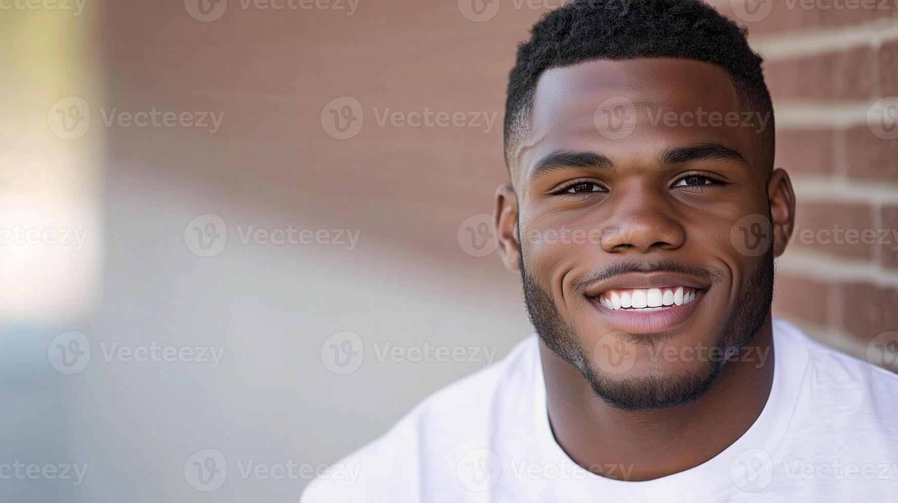 Happy african american man smiling by brick wall photo