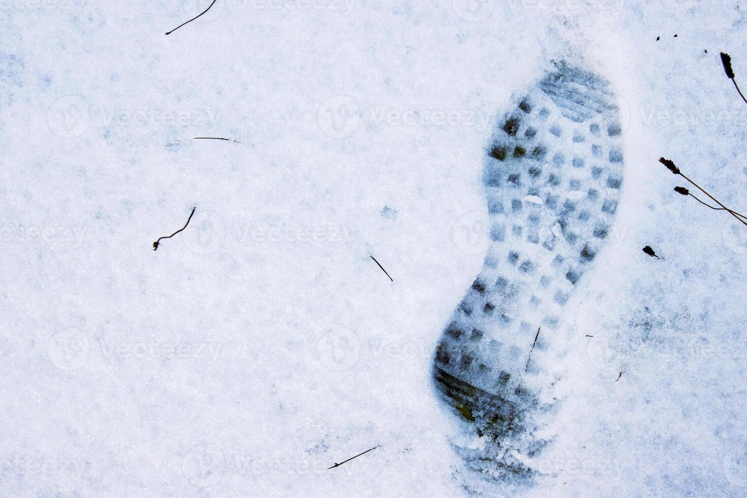 Closeup of a single black footprint in a white snow left by a boot, symbolizing color and texture contrast and outdoor adventure on a cold winter day. Copy space photo