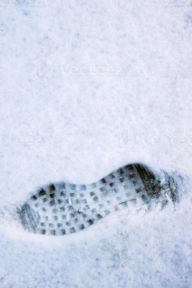 Closeup of a single black footprint in a white snow left by a boot, symbolizing color and texture contrast and outdoor adventure on a cold winter day. Copy space photo