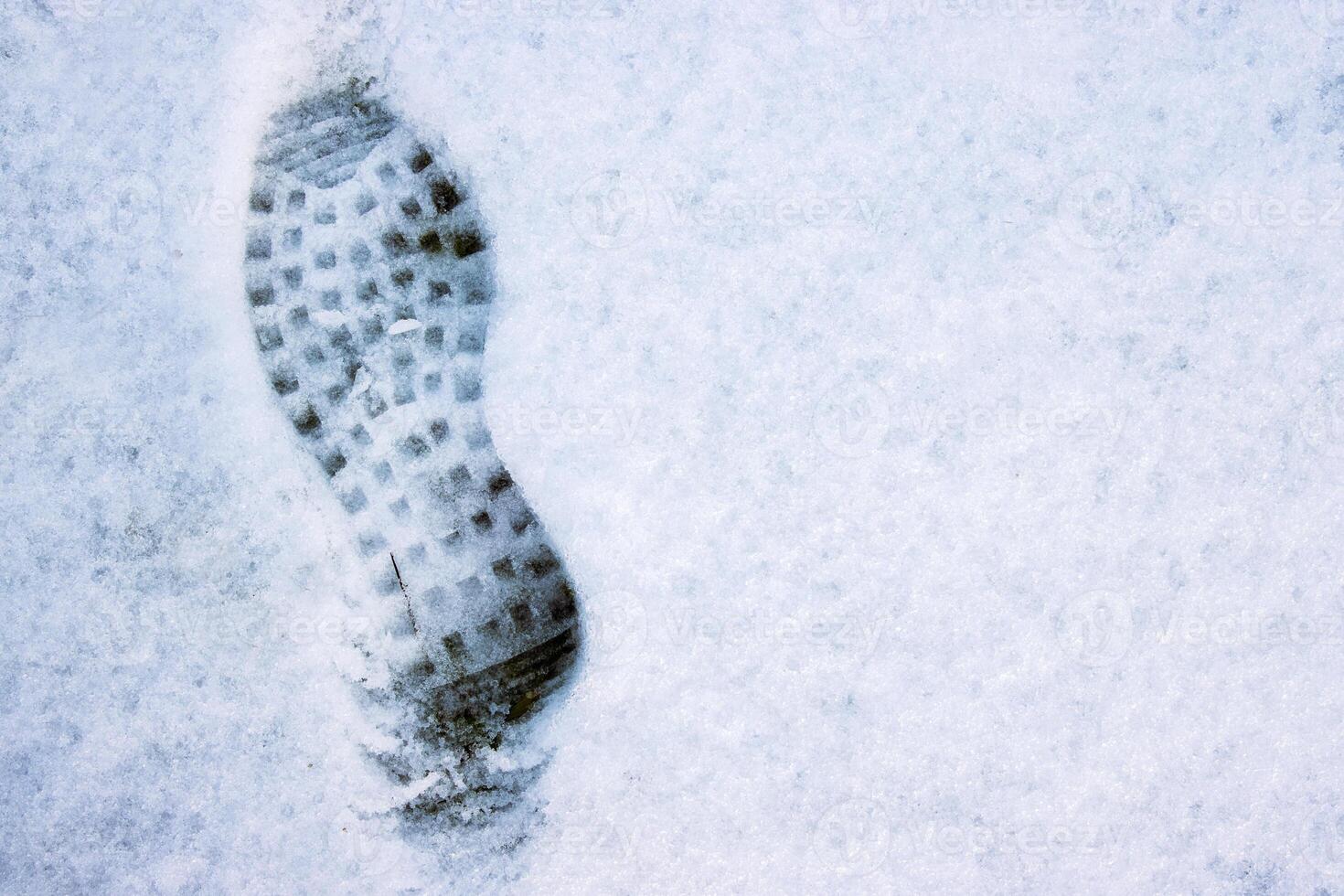 Closeup of a single black footprint in a white snow left by a boot, symbolizing color and texture contrast and outdoor adventure on a cold winter day. Copy space photo