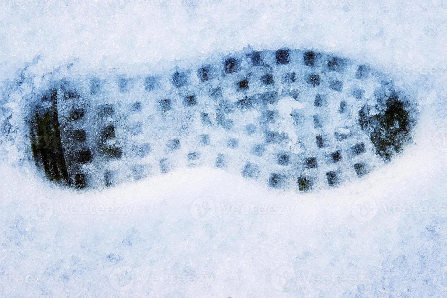 Closeup of a single black footprint in a white snow left by a boot, symbolizing color and texture contrast and outdoor adventure on a cold winter day. Copy space photo