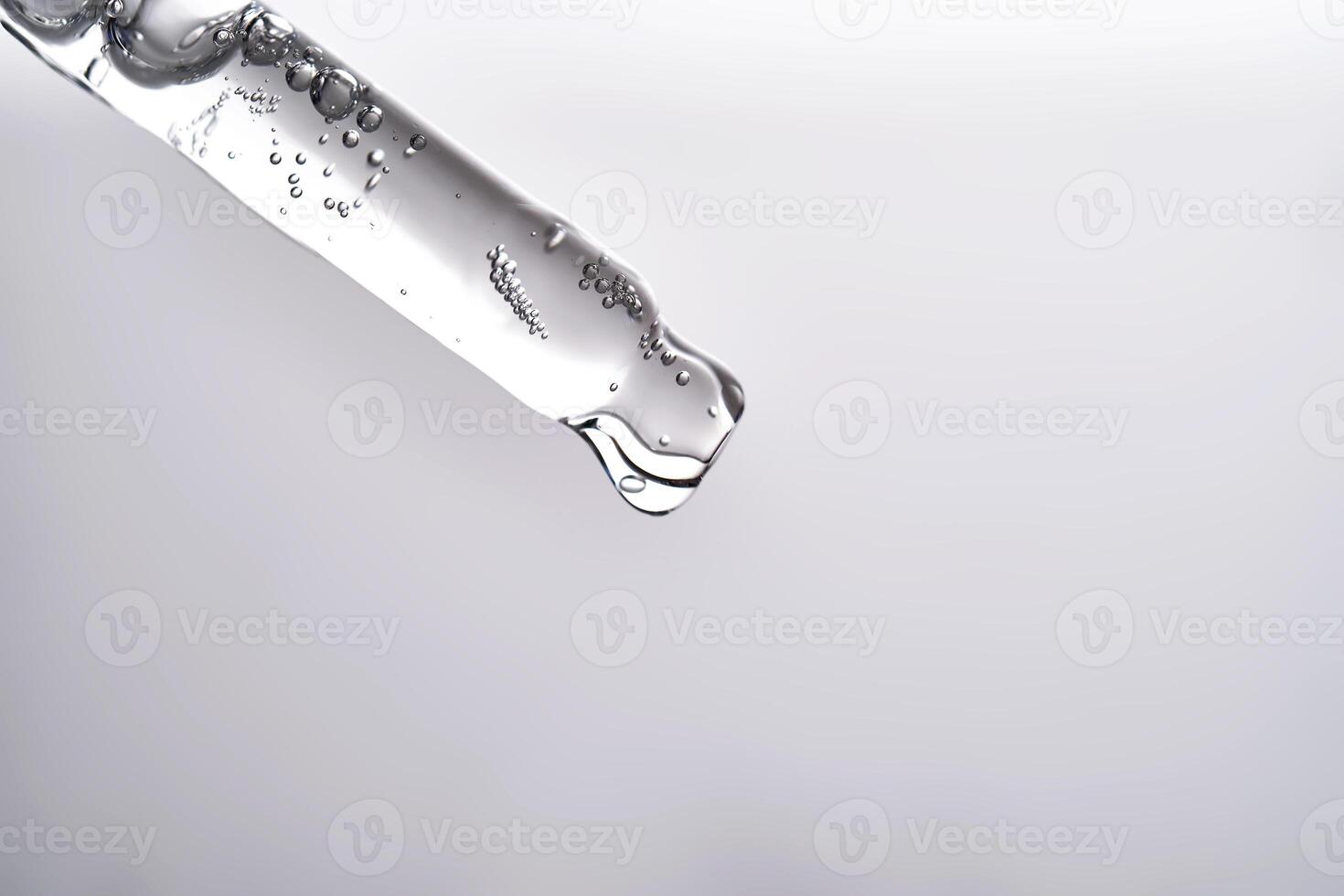 Pipette with facial serum pouring out of it on grey background. photo