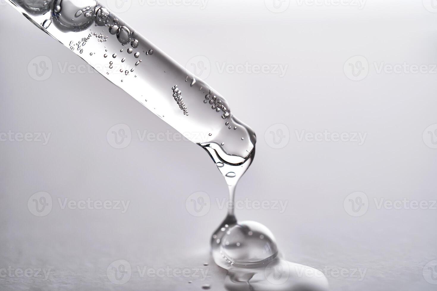 Pipette with facial serum pouring out of it on grey background. photo