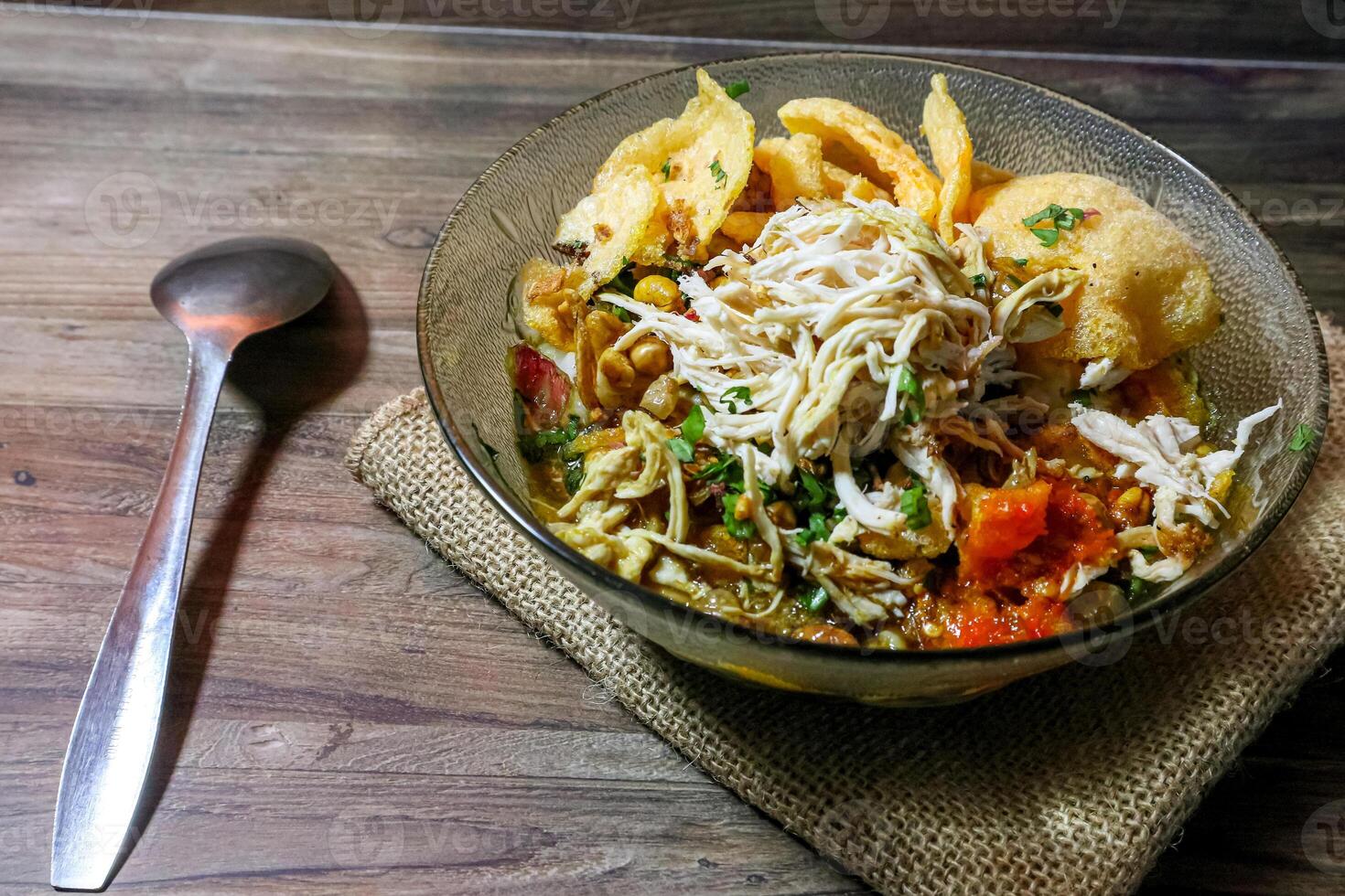Chicken porridge in a bowl with shredded chicken topping, crackers and typical Indonesian chili sauce photo